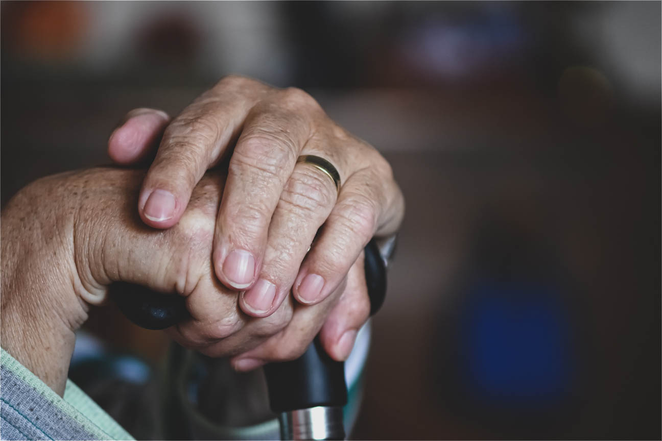 Elderly person's hands holding a cane